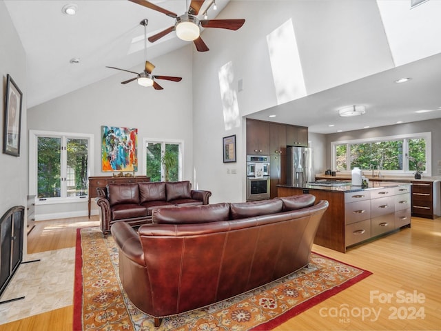 living room with sink, high vaulted ceiling, light hardwood / wood-style flooring, and ceiling fan