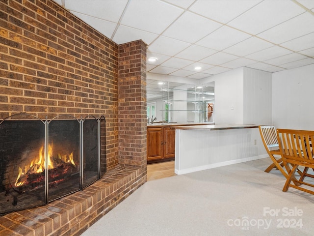 bar with light carpet, a fireplace, a paneled ceiling, and sink