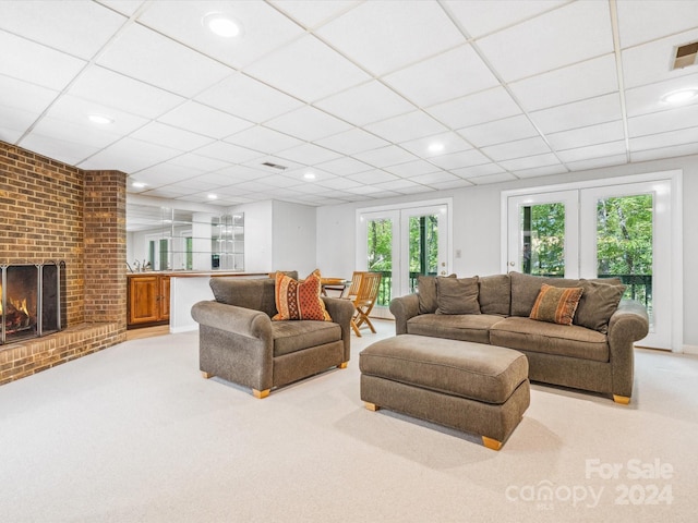 living room featuring light carpet, a brick fireplace, a paneled ceiling, and french doors