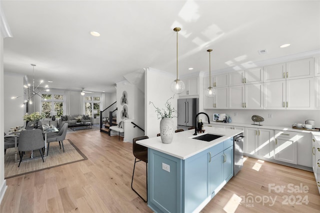 kitchen featuring white cabinets, sink, light hardwood / wood-style flooring, an island with sink, and stainless steel appliances