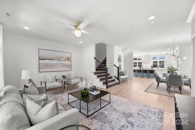 living room with light hardwood / wood-style floors and ceiling fan with notable chandelier