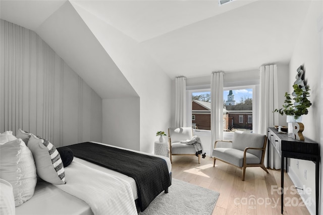 bedroom featuring light hardwood / wood-style floors and lofted ceiling