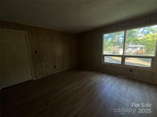 empty room featuring crown molding, dark hardwood / wood-style floors, and a textured ceiling