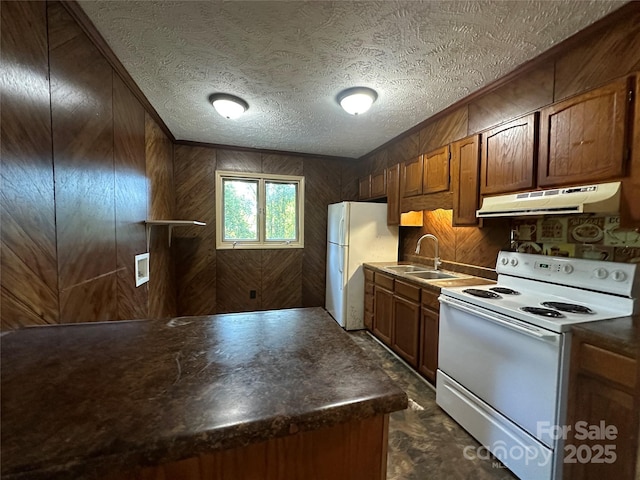 kitchen with white appliances, wooden walls, sink, and a textured ceiling