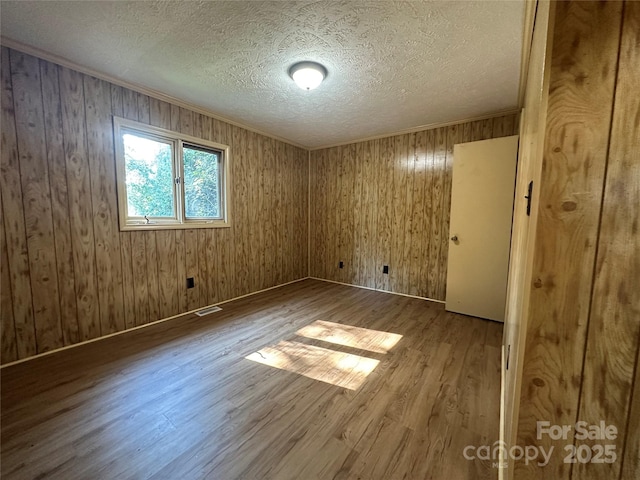 spare room featuring wood-type flooring, crown molding, and a textured ceiling