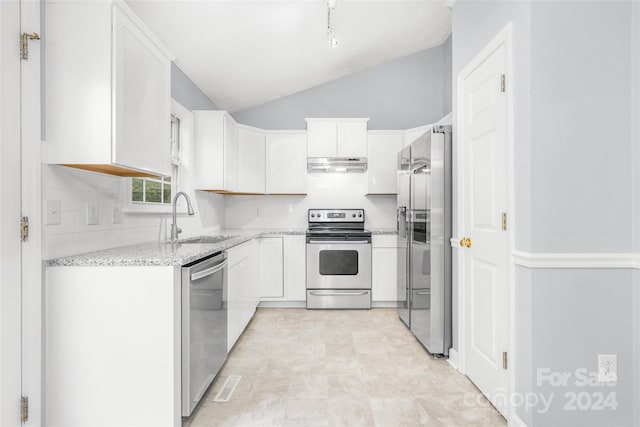 kitchen featuring appliances with stainless steel finishes, light stone counters, white cabinets, lofted ceiling, and sink