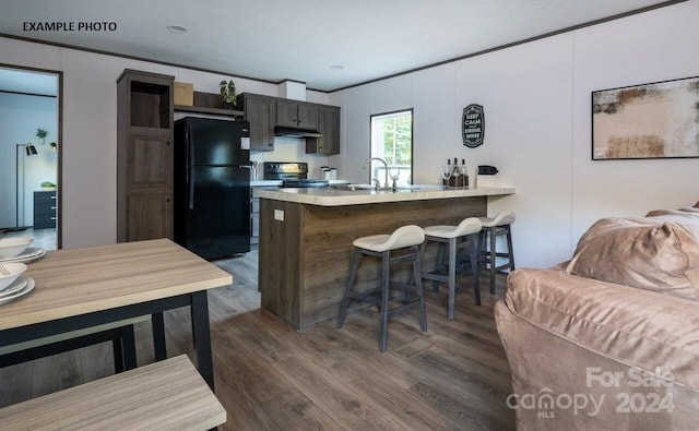 kitchen featuring sink, kitchen peninsula, black appliances, dark hardwood / wood-style floors, and a breakfast bar