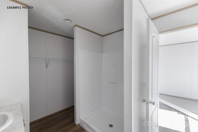 bathroom with wood-type flooring, a textured ceiling, walk in shower, and vanity