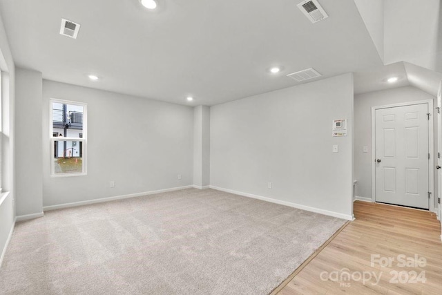 empty room with light hardwood / wood-style floors and lofted ceiling