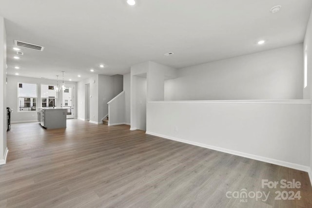 unfurnished living room featuring wood-type flooring and a chandelier