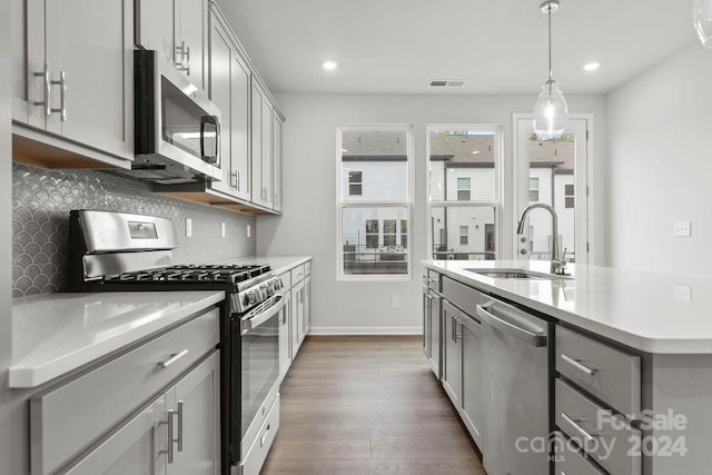 kitchen with backsplash, gray cabinets, stainless steel appliances, dark hardwood / wood-style floors, and sink