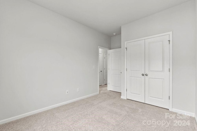 unfurnished bedroom with light carpet and a closet