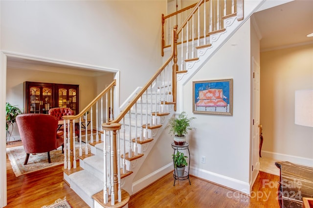 stairs featuring a towering ceiling, wood-type flooring, ornamental molding, and french doors