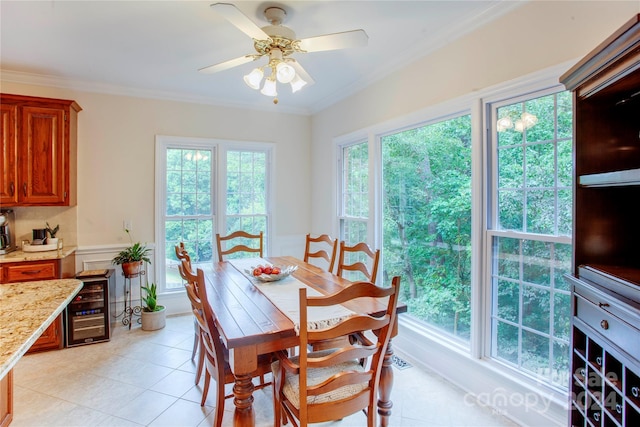 tiled dining room featuring ceiling fan, plenty of natural light, beverage cooler, and crown molding