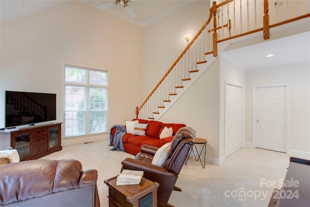 carpeted living room featuring ceiling fan and a high ceiling