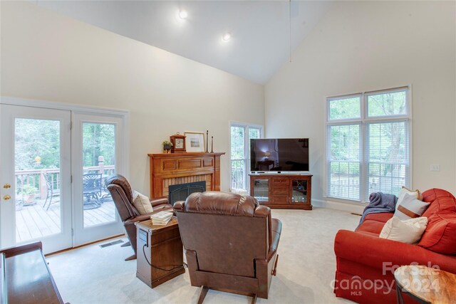 living room with high vaulted ceiling, light carpet, and a brick fireplace