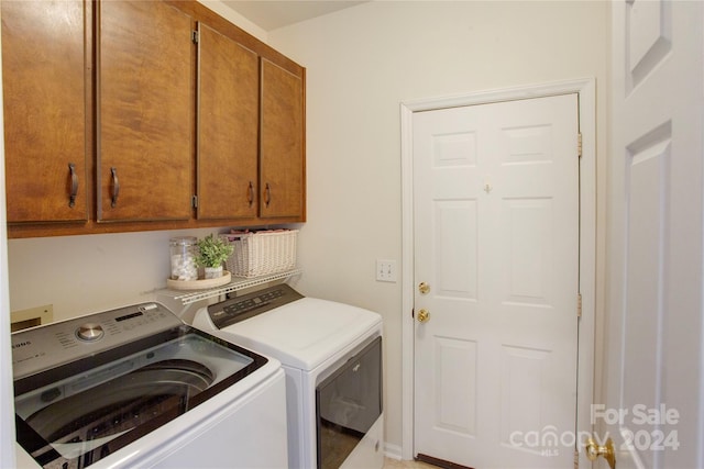 clothes washing area featuring washing machine and clothes dryer and cabinets