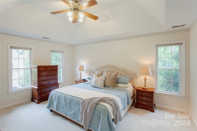 bedroom featuring ceiling fan, multiple windows, and light carpet