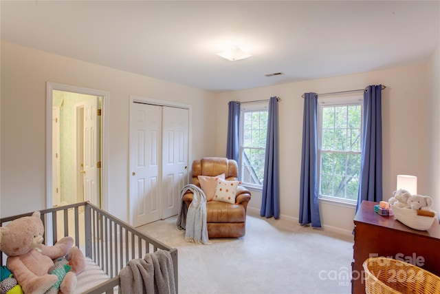 carpeted bedroom with a closet and a nursery area