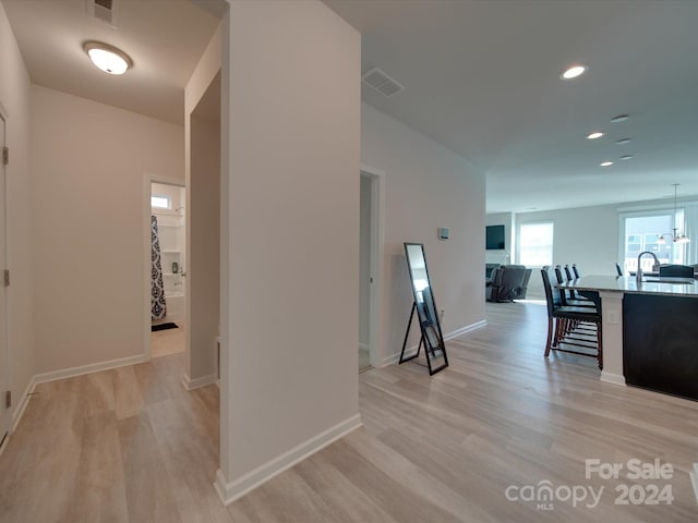 hallway with light wood-type flooring and sink