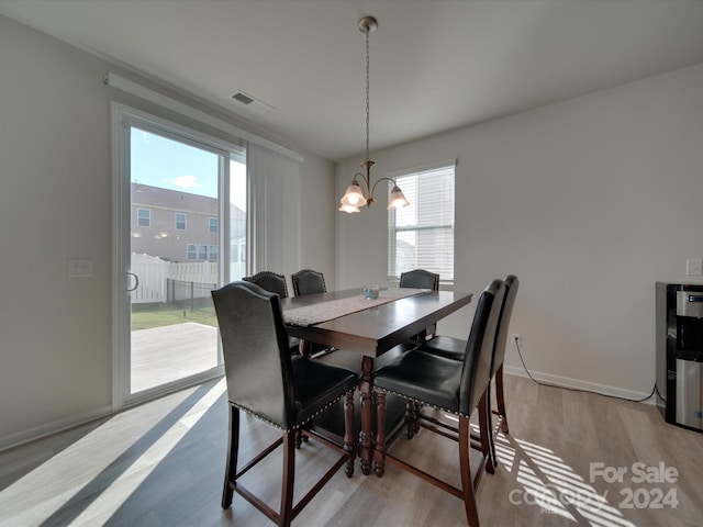 dining room with light wood-type flooring, a chandelier, and a healthy amount of sunlight