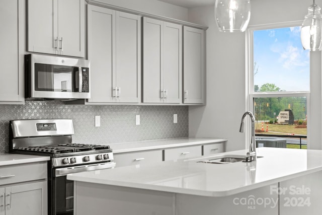 kitchen with a healthy amount of sunlight, sink, stainless steel appliances, and decorative light fixtures