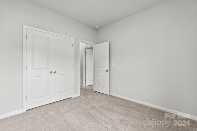 unfurnished bedroom with light carpet and a closet