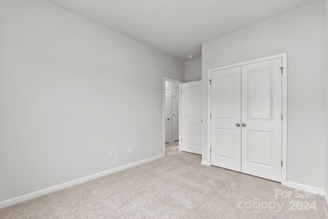 unfurnished bedroom featuring light carpet and a closet