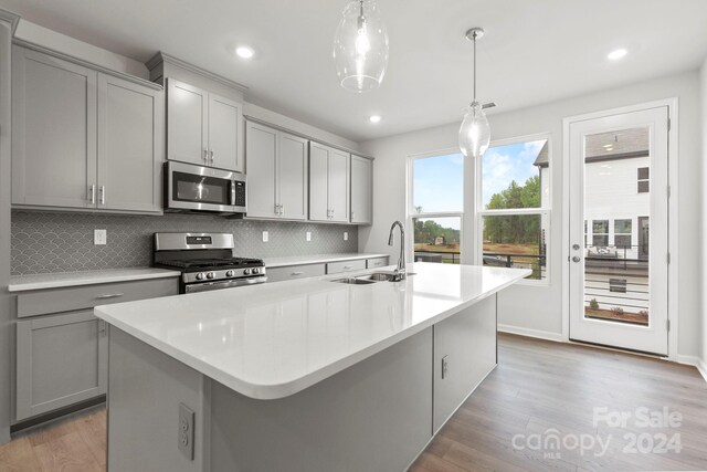 kitchen with gray cabinets, appliances with stainless steel finishes, and hanging light fixtures