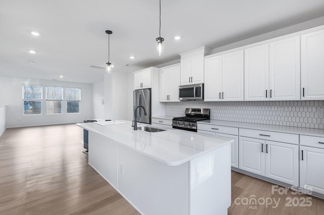 kitchen featuring appliances with stainless steel finishes, sink, an island with sink, and white cabinetry