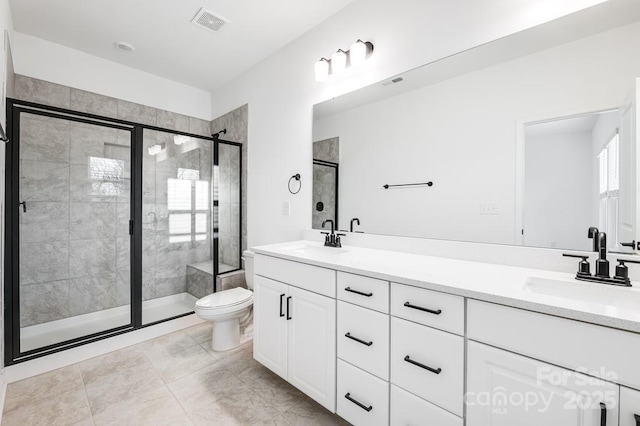 bathroom featuring toilet, vanity, and a shower with shower door