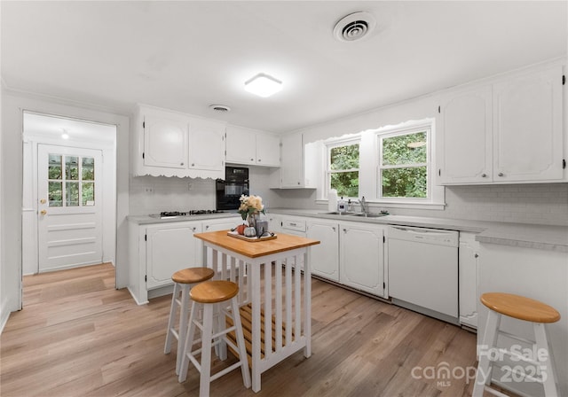 kitchen featuring white dishwasher, backsplash, black oven, and white cabinets