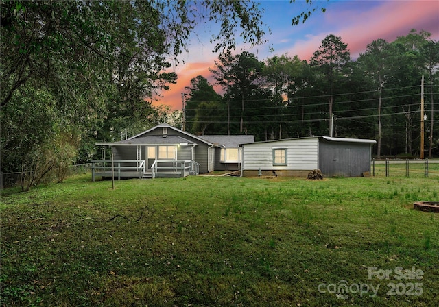 back house at dusk featuring a deck and a lawn