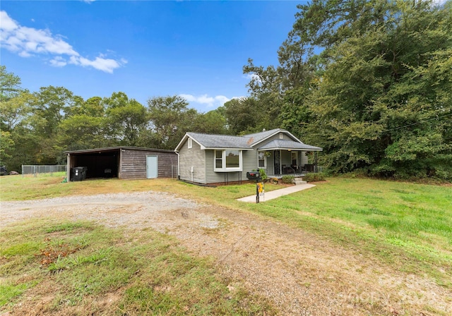 view of front of property featuring an outbuilding, covered porch, and a front lawn