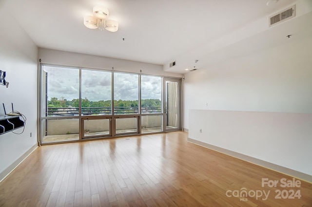 spare room with light hardwood / wood-style flooring and a chandelier