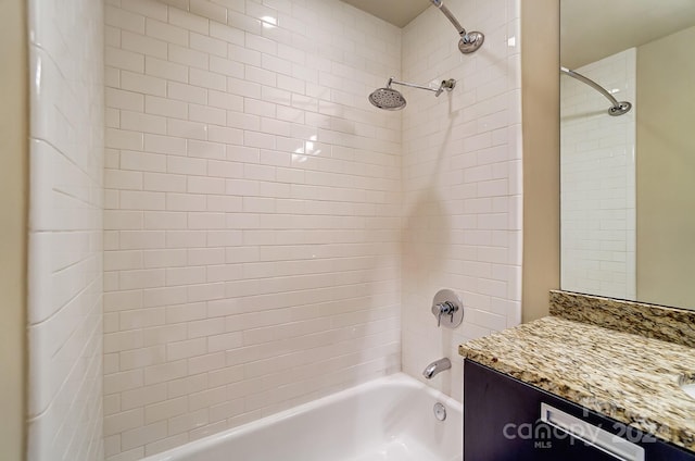 bathroom with tiled shower / bath combo and vanity