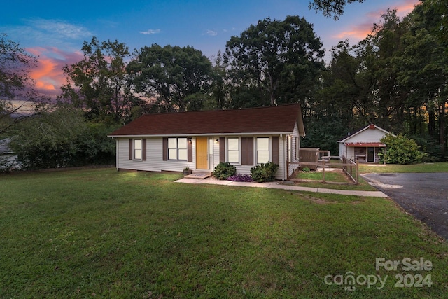 ranch-style home with a lawn and an outbuilding