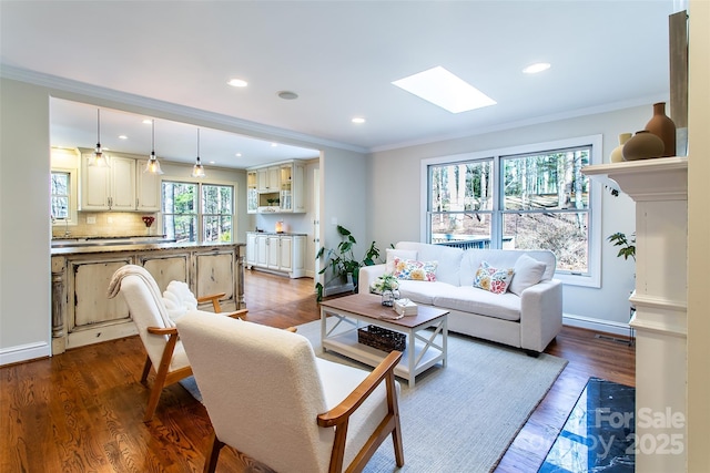 living room with ornamental molding, plenty of natural light, hardwood / wood-style floors, and a skylight