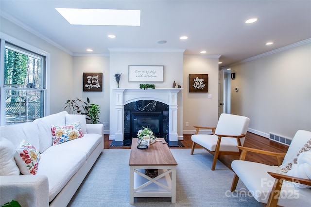 living room with crown molding, hardwood / wood-style floors, a high end fireplace, and a skylight