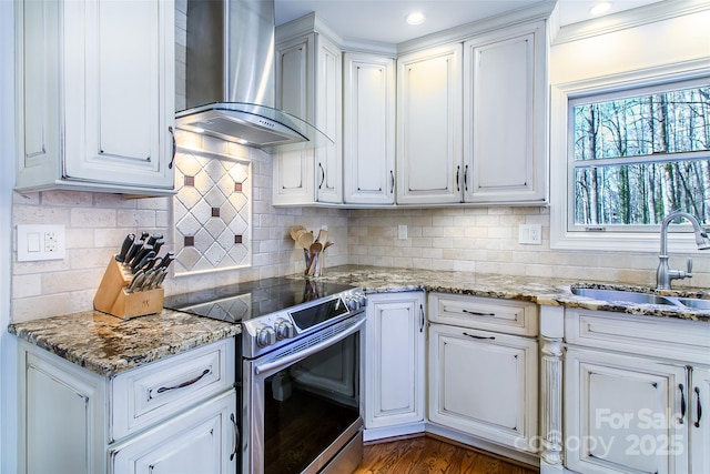 kitchen featuring white cabinets, decorative backsplash, wall chimney exhaust hood, and stainless steel electric range oven