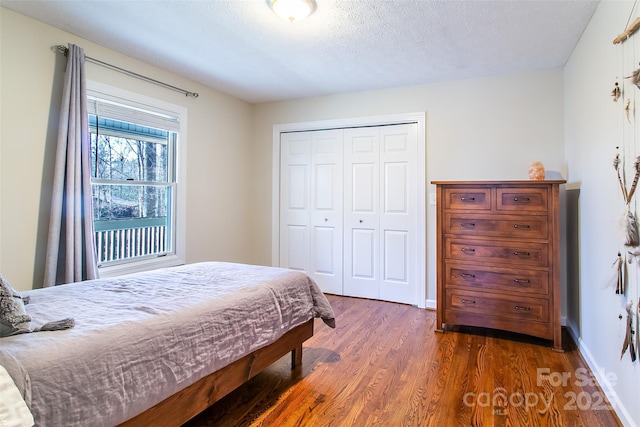 bedroom featuring dark wood-type flooring, a closet, and a textured ceiling