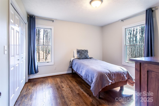 bedroom with multiple windows, a textured ceiling, dark hardwood / wood-style flooring, and a closet