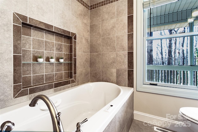 bathroom featuring tile patterned floors, toilet, and tiled tub