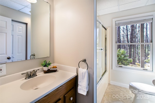 full bathroom featuring a paneled ceiling, combined bath / shower with glass door, vanity, tile patterned floors, and toilet