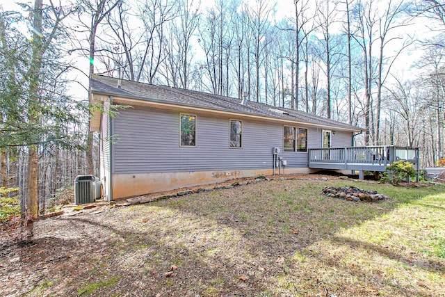 back of property featuring a wooden deck, central AC unit, and a lawn