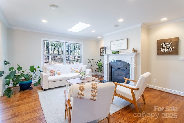 living room with a premium fireplace, wood-type flooring, ornamental molding, and a skylight