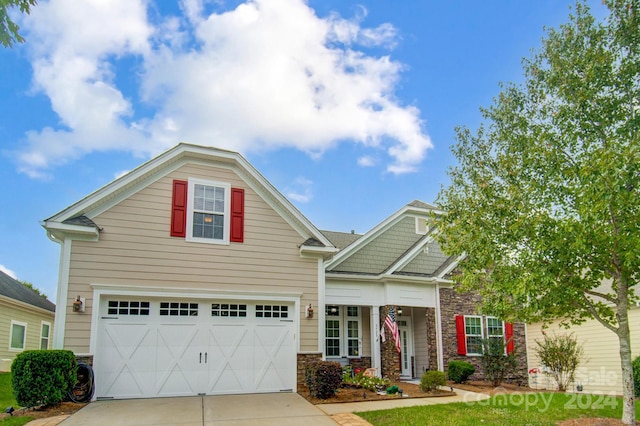 craftsman-style house with a garage, driveway, and stone siding
