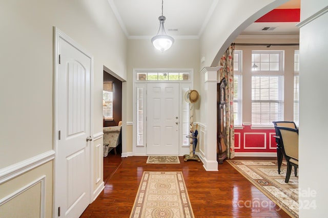 foyer entrance with arched walkways, crown molding, dark wood-style flooring, and visible vents