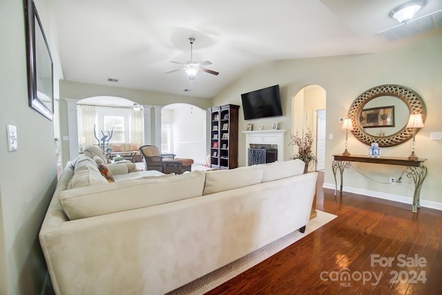 living area featuring arched walkways, dark wood finished floors, decorative columns, visible vents, and ceiling fan