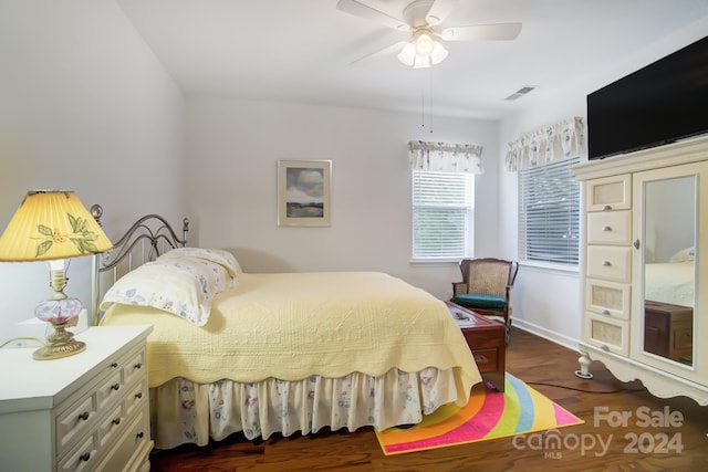 bedroom with wood finished floors, visible vents, a ceiling fan, and baseboards